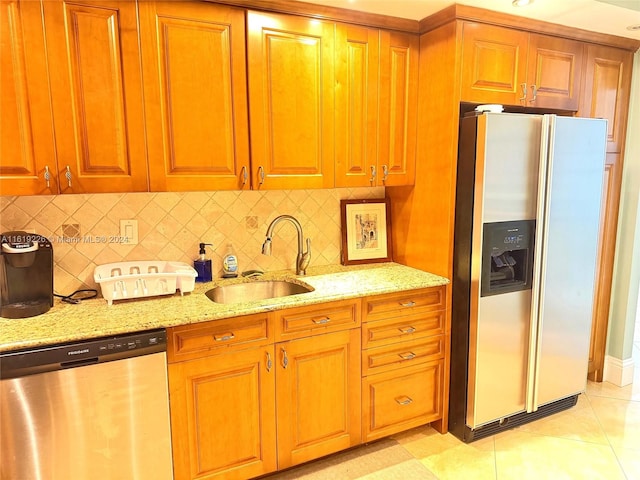 kitchen featuring light tile patterned flooring, appliances with stainless steel finishes, sink, and light stone countertops