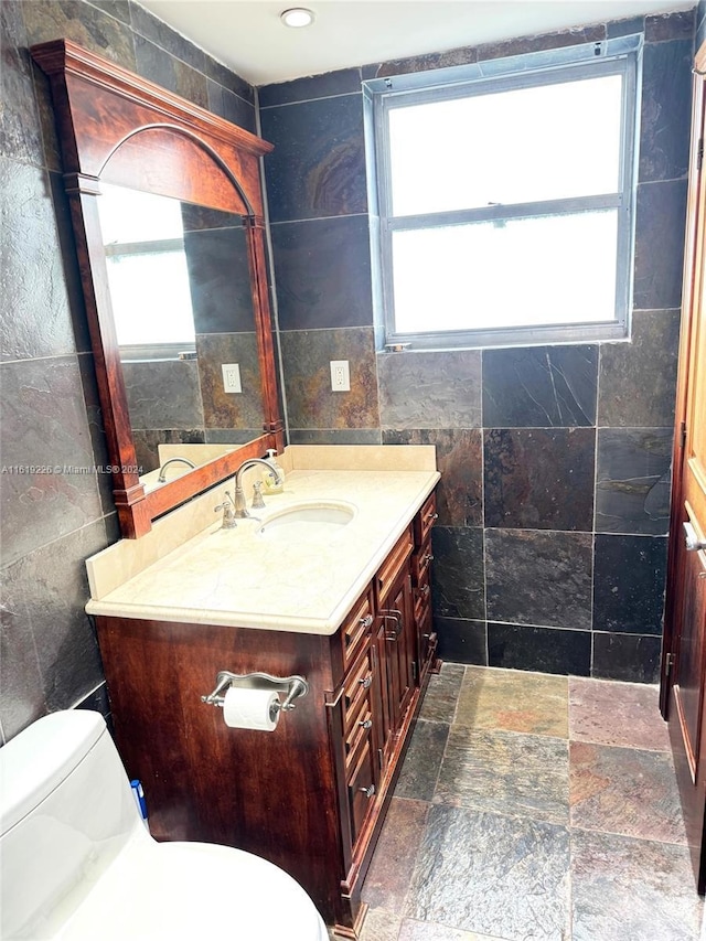 bathroom with toilet, tile walls, and vanity