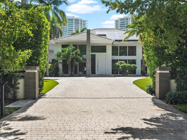 single story home featuring curved driveway and roof mounted solar panels