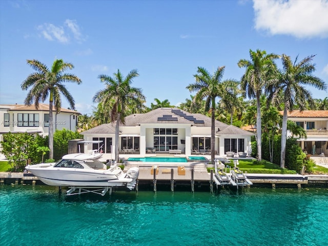 rear view of house with an outdoor pool, a patio area, boat lift, and solar panels