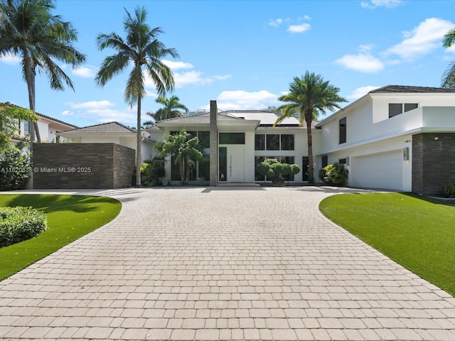 view of front of house with a garage, decorative driveway, a front lawn, and stucco siding