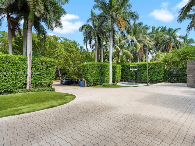 surrounding community featuring decorative driveway and a lawn