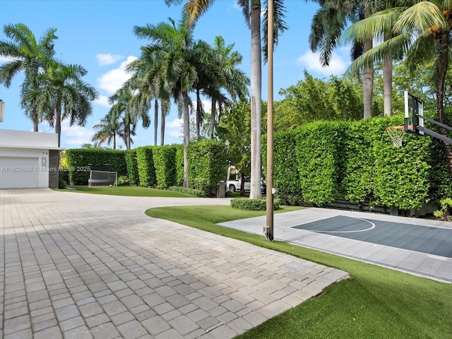 view of sport court featuring basketball hoop and a yard