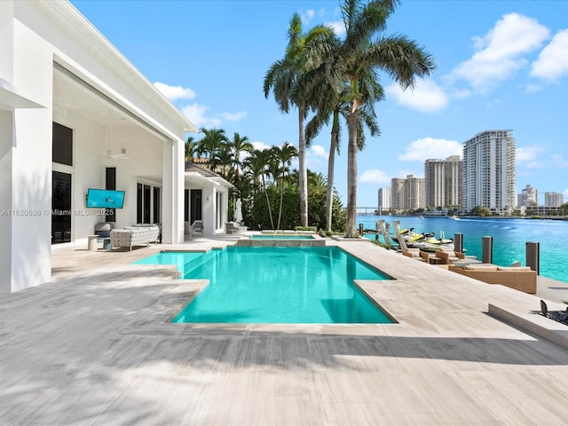 view of swimming pool with a water view, a patio area, a pool with connected hot tub, and a city view