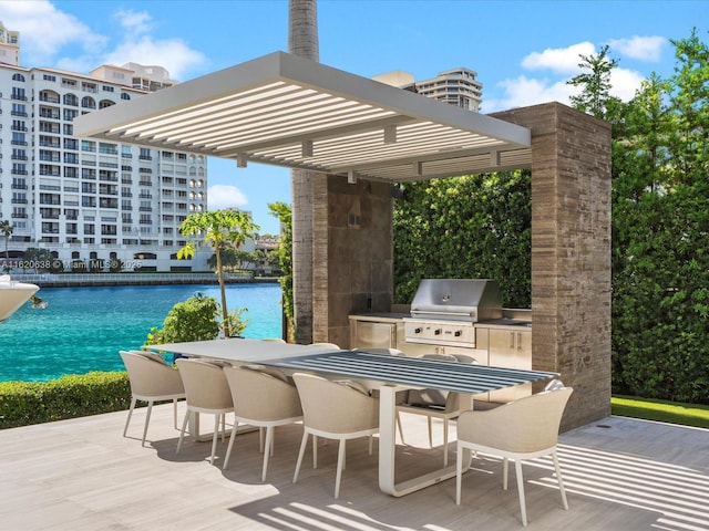 view of patio / terrace with grilling area, a water view, exterior kitchen, outdoor wet bar, and a pergola