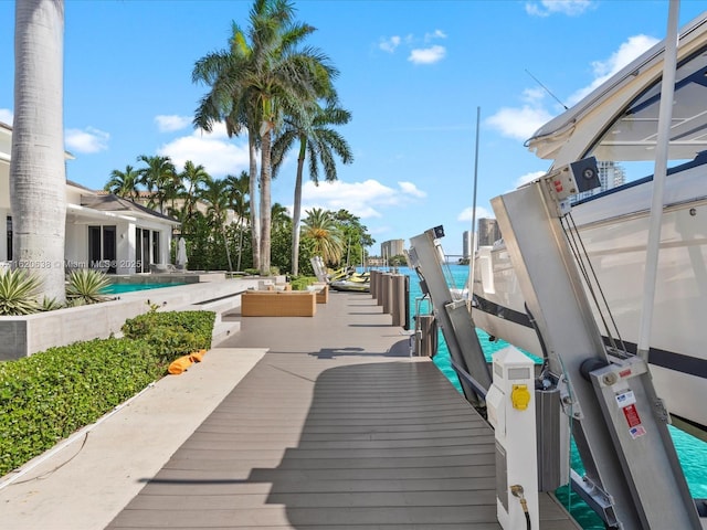 view of home's community with a water view, boat lift, a pool, and a patio