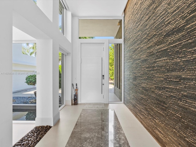 foyer featuring an accent wall, a towering ceiling, and floor to ceiling windows