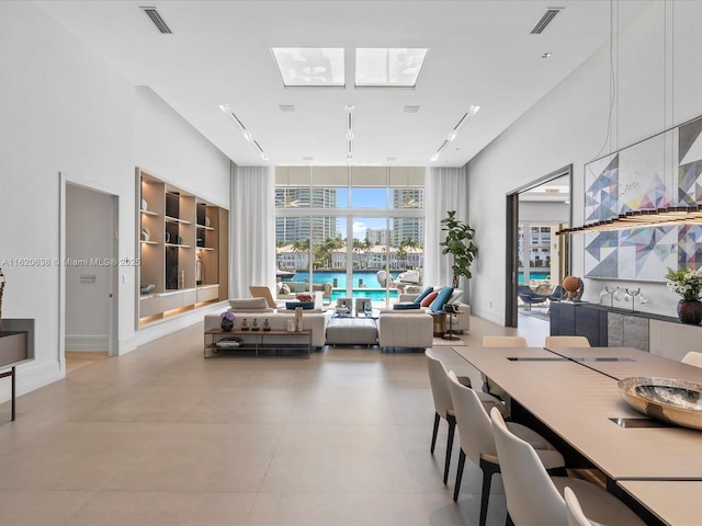 dining space featuring visible vents, built in features, a skylight, and expansive windows