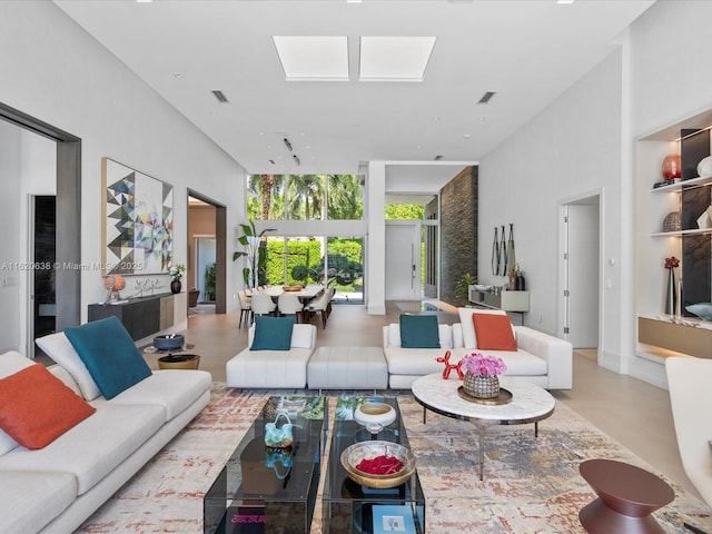 living room featuring a high ceiling, a skylight, and visible vents