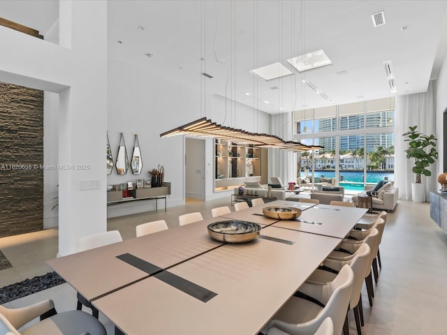 dining room with a wall of windows, visible vents, and a towering ceiling