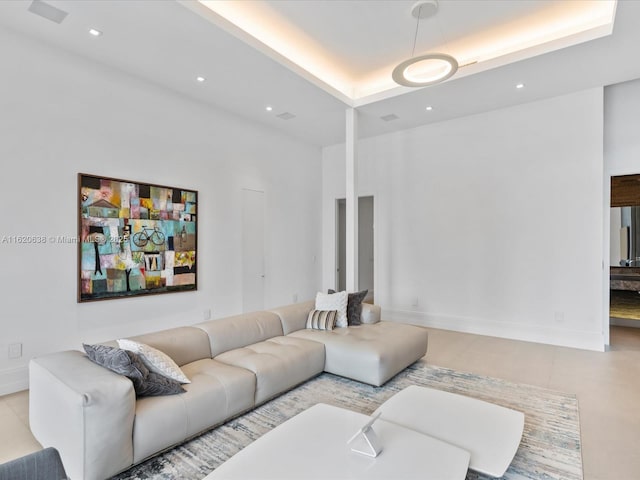 living room featuring recessed lighting, a raised ceiling, a high ceiling, and baseboards