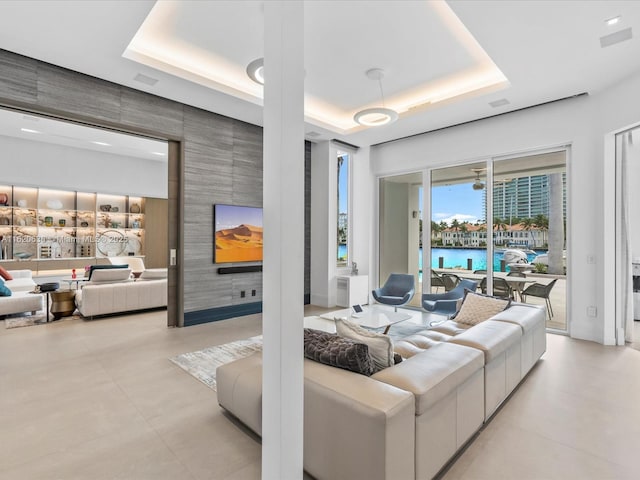 living room with a tray ceiling and an accent wall