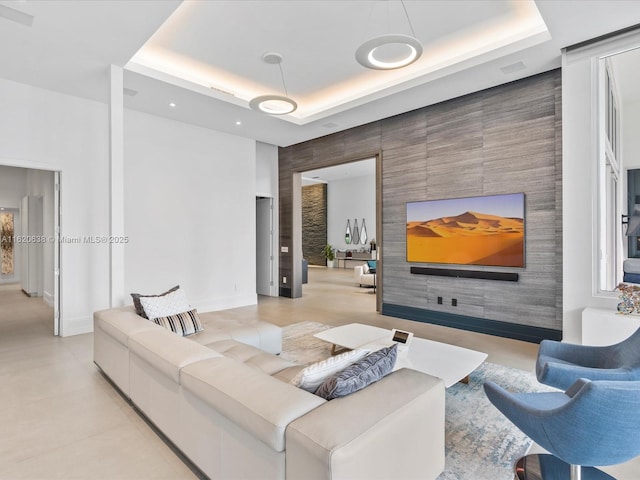 living room with baseboards, an accent wall, and a tray ceiling