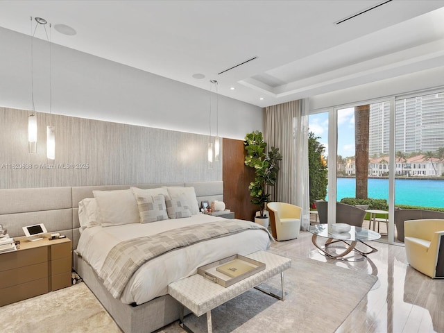 bedroom with access to outside, a tray ceiling, and a water view