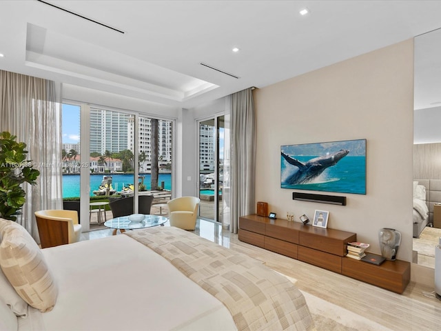 bedroom with a tray ceiling, recessed lighting, wood finished floors, and access to exterior