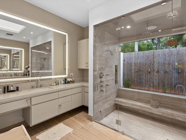 full bath with vanity, visible vents, wood finished floors, and a stall shower