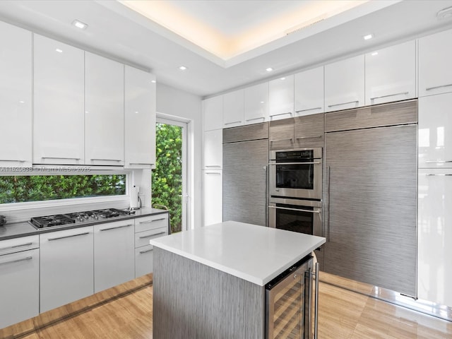 kitchen featuring beverage cooler, appliances with stainless steel finishes, and white cabinets