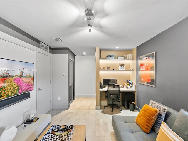 office space featuring visible vents, light wood-style flooring, and built in study area