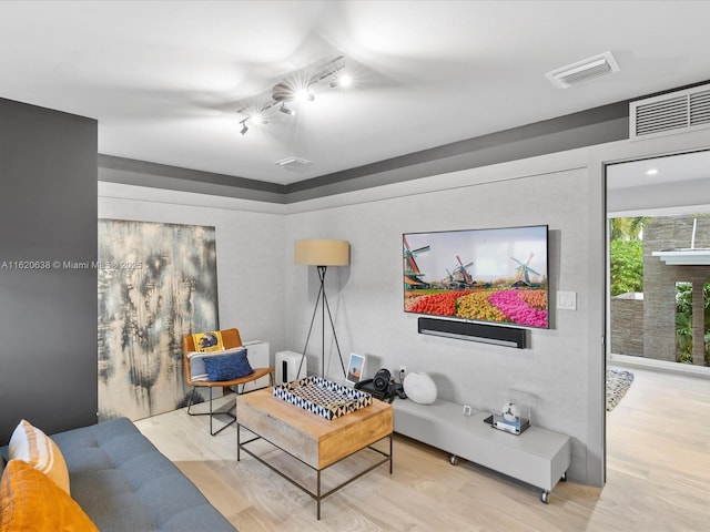 living area with visible vents and wood finished floors