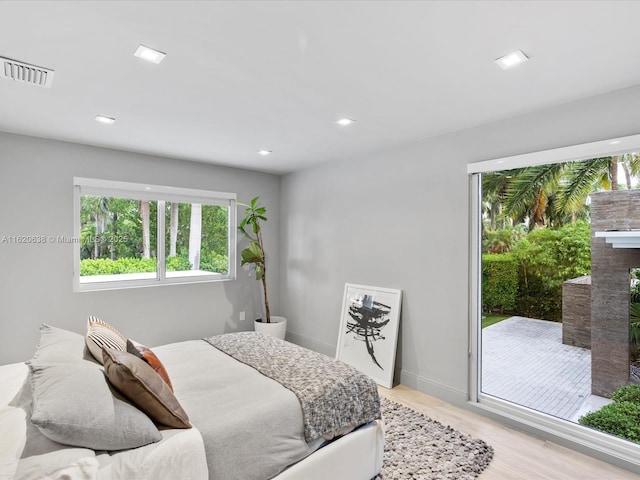 bedroom with a fireplace, light wood finished floors, recessed lighting, visible vents, and baseboards