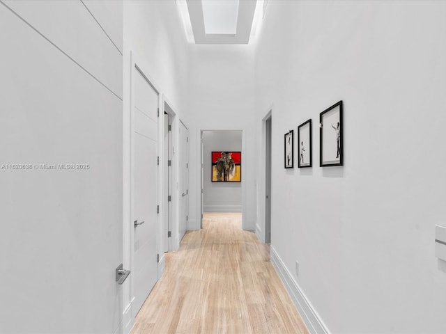 corridor with light wood-style floors and baseboards