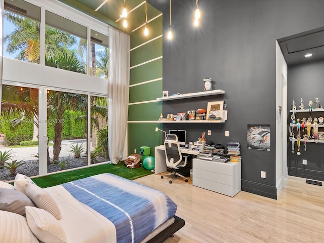 bedroom featuring a towering ceiling, baseboards, and wood finished floors