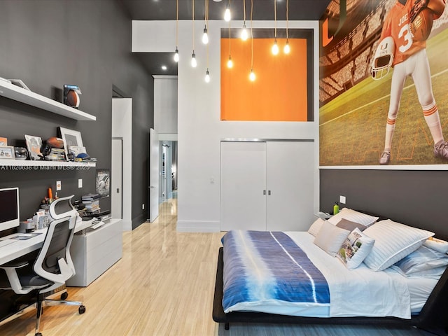 bedroom featuring a closet, a towering ceiling, baseboards, and wood finished floors