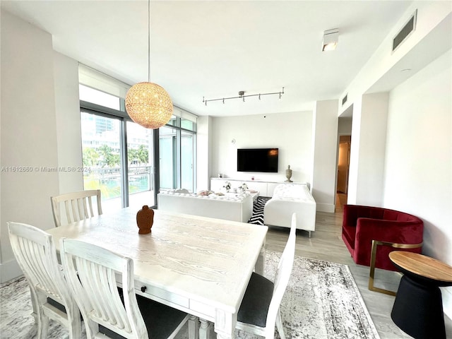 dining area with light wood-type flooring and track lighting