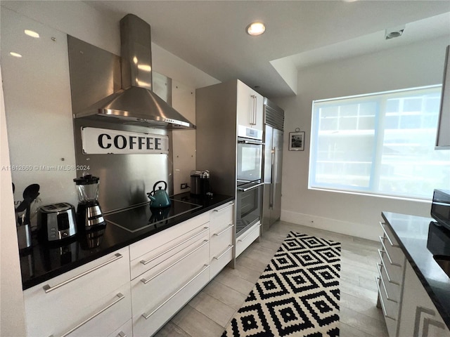 kitchen with white cabinetry, black electric stovetop, double oven, and range hood