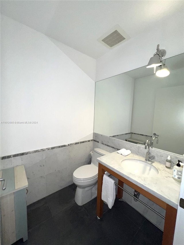 bathroom featuring toilet, vanity, tile walls, and tile patterned flooring