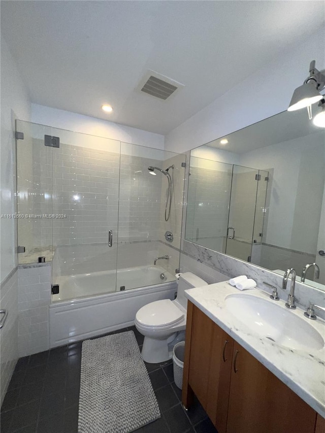 full bathroom featuring toilet, bath / shower combo with glass door, tile patterned floors, and vanity