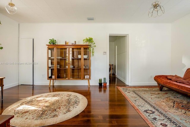 living area with dark wood-type flooring and ornamental molding