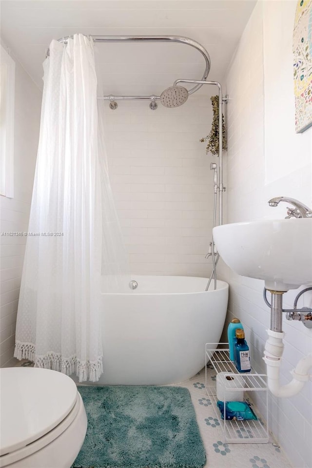 full bathroom with shower / bath combo with shower curtain, sink, toilet, and tile walls