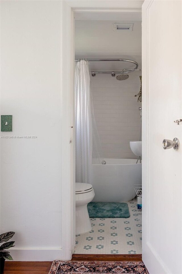 bathroom with shower / bath combo with shower curtain and toilet