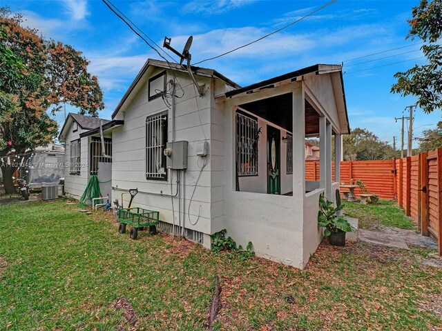 view of side of property featuring central AC and a yard