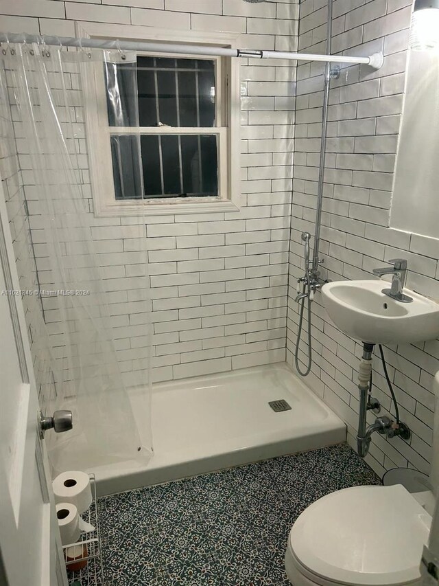 bathroom featuring tile patterned flooring, tasteful backsplash, toilet, tile walls, and sink