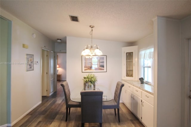 dining room with dark hardwood / wood-style floors, an inviting chandelier, and a textured ceiling