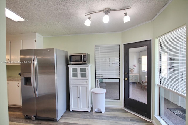 kitchen with white cabinetry, ornamental molding, a textured ceiling, and appliances with stainless steel finishes