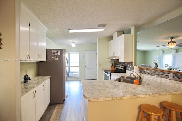 kitchen featuring stainless steel appliances, kitchen peninsula, sink, and white cabinets