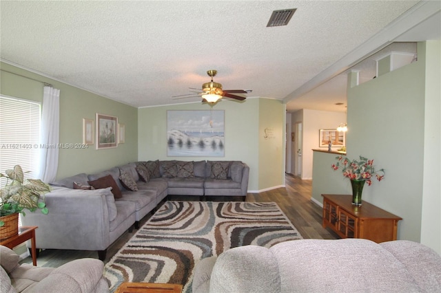 living room featuring dark hardwood / wood-style flooring, ceiling fan, and a textured ceiling