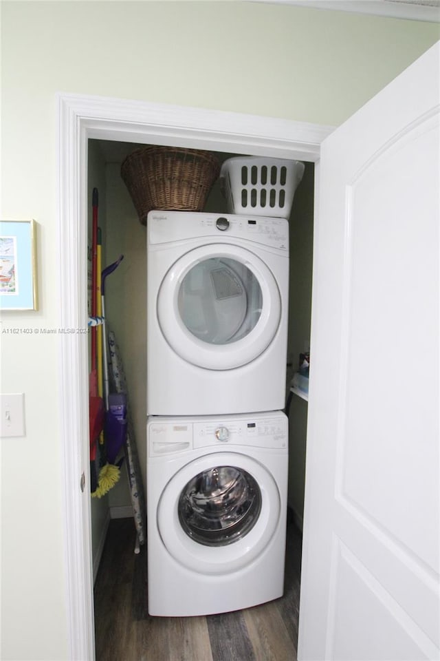 clothes washing area featuring dark wood-type flooring and stacked washer and clothes dryer