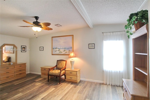 living area with vaulted ceiling with beams, hardwood / wood-style flooring, a textured ceiling, and ceiling fan