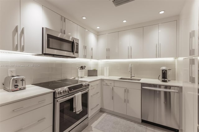 kitchen featuring stainless steel appliances, sink, decorative backsplash, and white cabinets