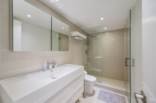 bathroom featuring vanity, a shower with shower door, tile walls, and toilet