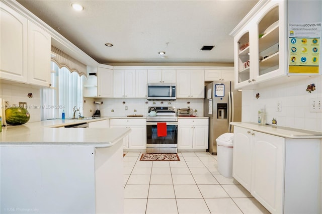 kitchen featuring decorative backsplash, stainless steel appliances, white cabinetry, and light tile patterned floors