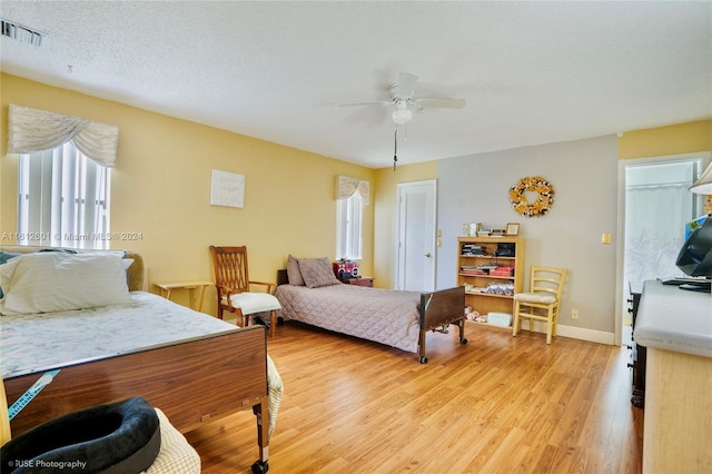 bedroom with light wood-type flooring, ceiling fan, and a textured ceiling