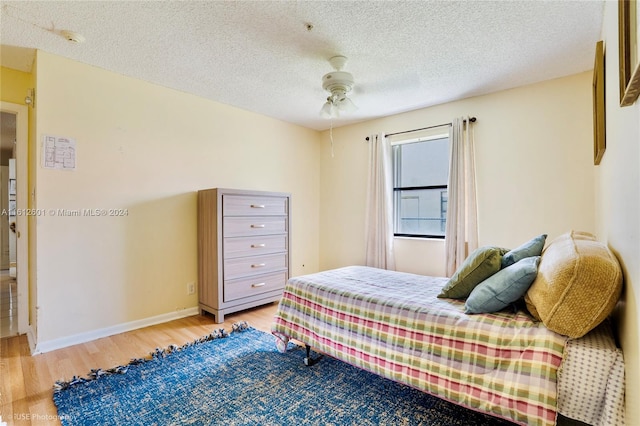 bedroom with a textured ceiling, ceiling fan, and light hardwood / wood-style floors