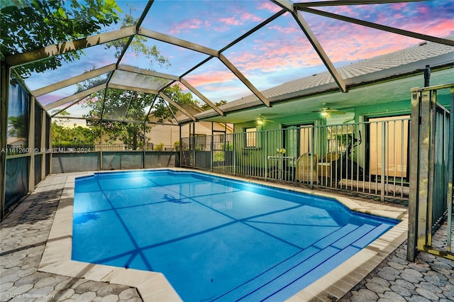 pool at dusk featuring a lanai