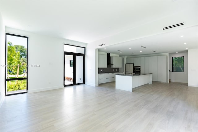 kitchen with white fridge, a kitchen island with sink, light hardwood / wood-style flooring, and plenty of natural light