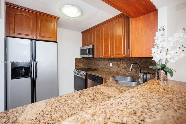 kitchen featuring light stone countertops, decorative backsplash, stainless steel appliances, and a sink